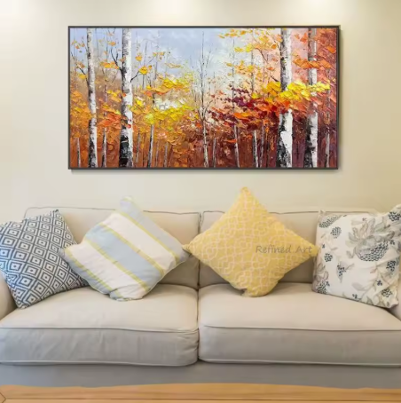 Sofa with decorative pillows and a large painting of a forest scene on the wall.