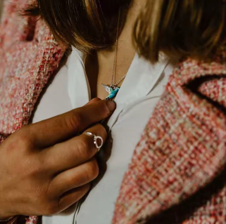 Person wearing a colorful butterfly necklace with a blazer