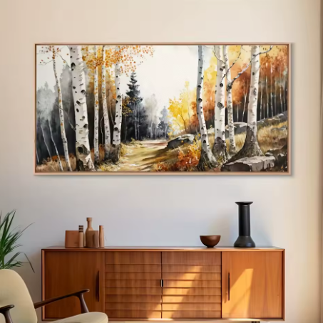 Framed landscape painting of a forest scene on a wall above a wooden cabinet.