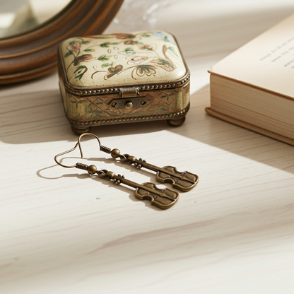 Antique-style earrings on a piece of paper with a decorative jewelry box in the background.