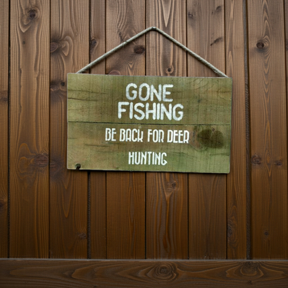 Wooden sign with text 'GONE FISHING BE BACK FOR DEER HUNTING' on a wooden background