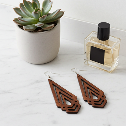 Wooden earrings on a marble surface with a potted succulent and perfume bottle.