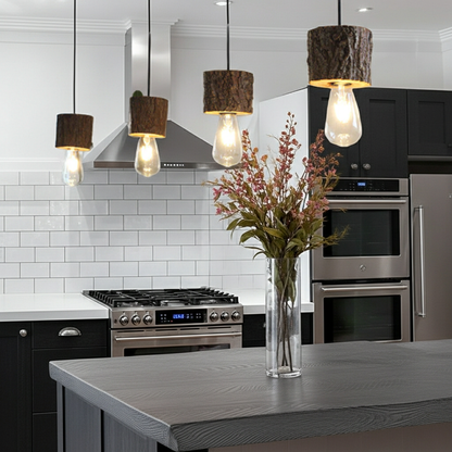 Modern kitchen with stainless steel appliances, pendant lights, and a vase of flowers on the island.