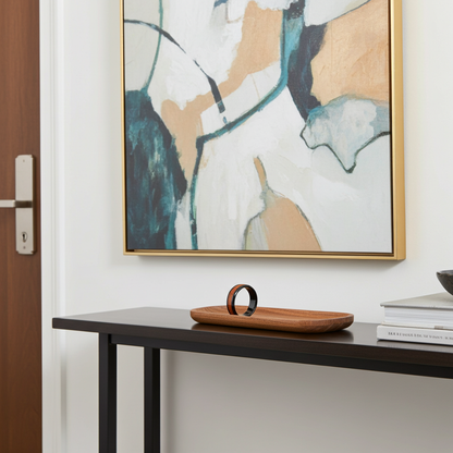 Abstract framed wall art with teal, cream, tan, and charcoal brushstrokes in a gold frame, displayed above a dark console table in a modern interior setting.