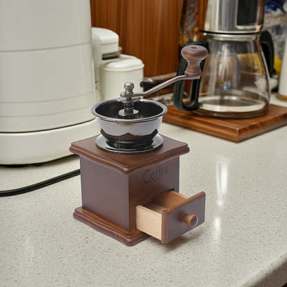 Wooden coffee grinder on a kitchen counter with coffee-making equipment in the background.