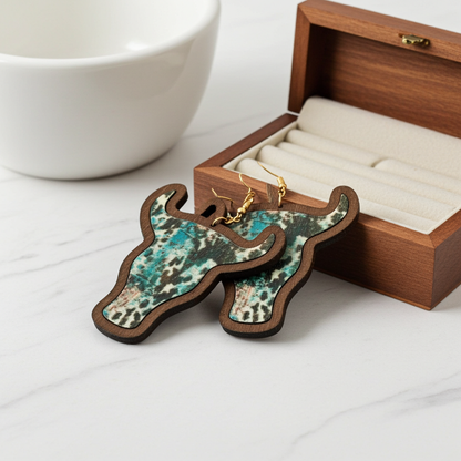 cow head earrings on a wooden display stand with a jewelry box in the background.