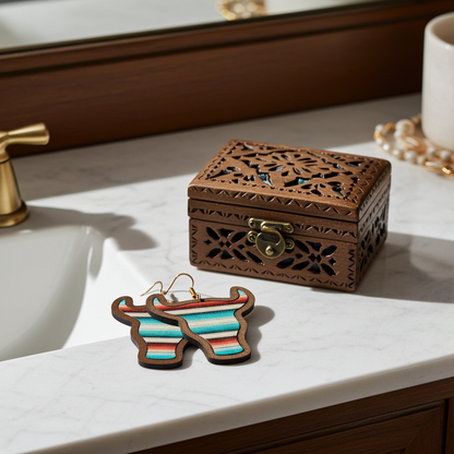 Wooden earrings with colorful stripes on a marble surface next to an ornate wooden box.