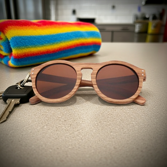 Wooden sunglasses with dark lenses on a kitchen counter next to keys and a colorful towel.