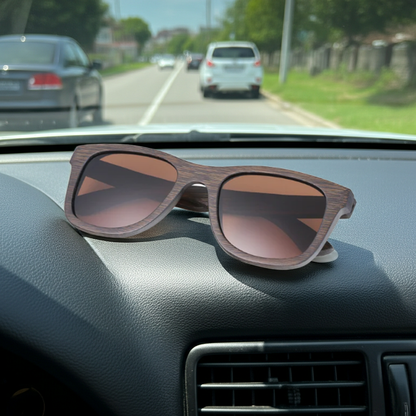Wooden sunglasses on a car dashboard with a road and vehicles in the background