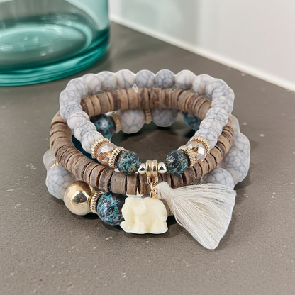 Stack of beaded bracelets with decorative elements on a gray surface