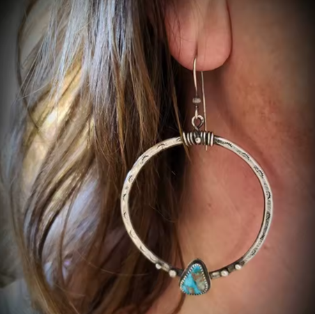 Silver hoop earring with turquoise stone worn by a person