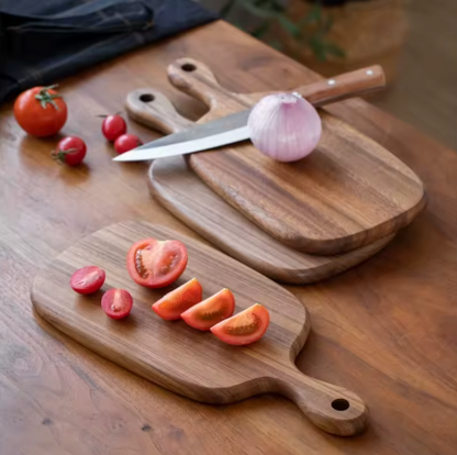 Wooden cutting boards with tomatoes and a knife on a wooden surface
