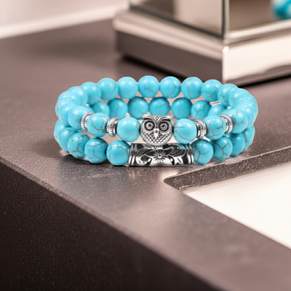 Turquoise beaded bracelet with an owl charm on a reflective surface