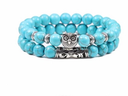 Turquoise beaded bracelet with owl and floral charm on a white background