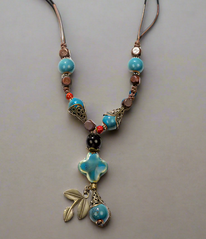 Necklace with blue beads and a floral pendant on a gray background