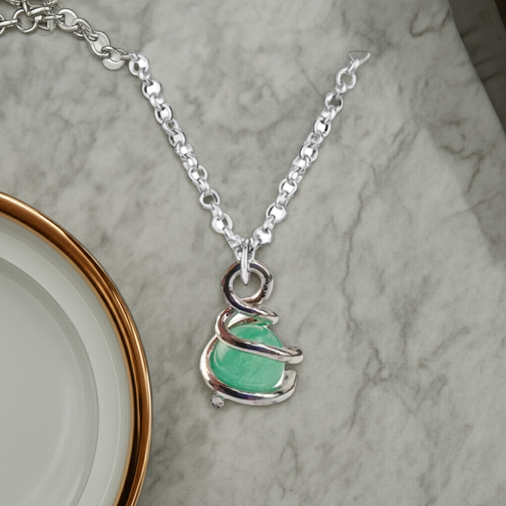 Silver necklace with a green pendant on a marble surface
