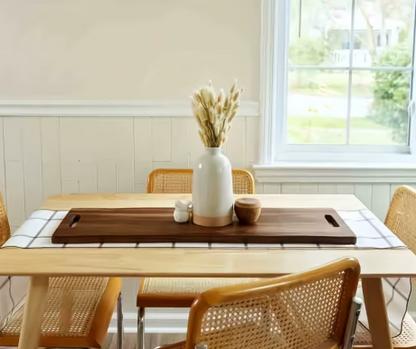 Dining room with a table set for a meal, featuring a vase with flowers and a cutting board.