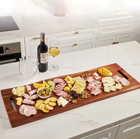 Wooden charcuterie board with assorted meats, cheeses, and fruits on a kitchen counter.