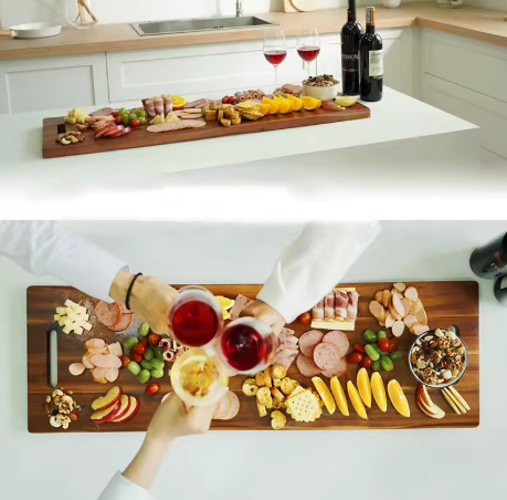 Two wooden platters with assorted food and wine glasses on a kitchen counter.