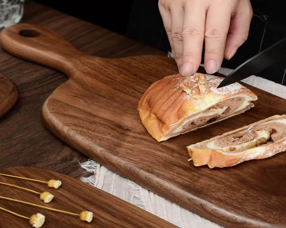 Person slicing a meatloaf on a wooden cutting board with a knife.