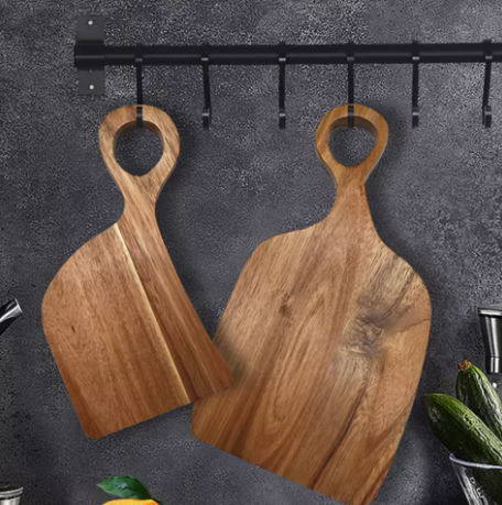 Two wooden cutting boards with handles hanging on a dark gray wall.