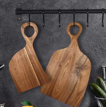 Two wooden cutting boards with handles hanging on a dark gray wall.