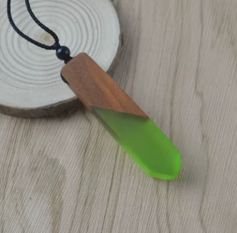 Necklace with a wooden pendant and green accent on a wooden surface