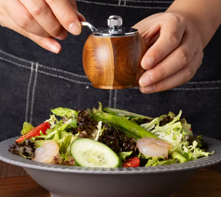 grinding pepper unto a salad