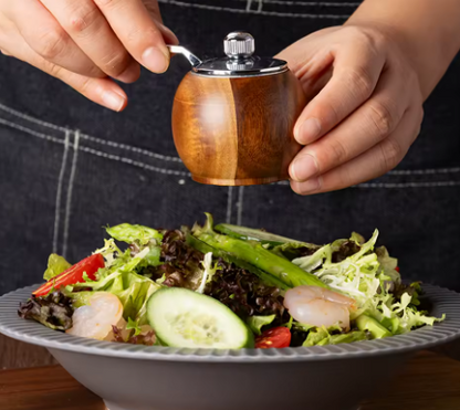 grinding pepper unto a salad