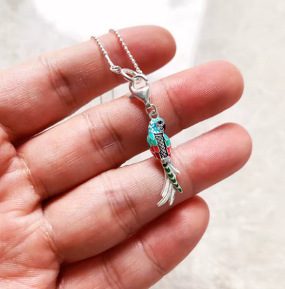 Necklace with a detailed pendant held between fingers against a neutral background