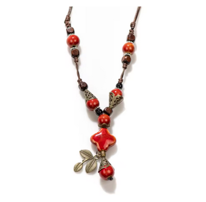 Necklace with orange beads and a leaf pendant on a white background