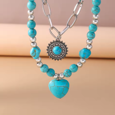 Turquoise beaded necklace with a heart pendant on a beige background