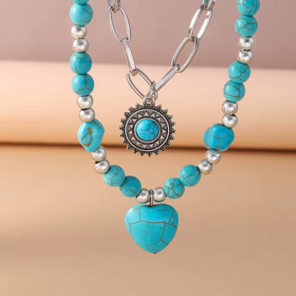 Turquoise beaded necklace with a heart pendant on a beige background