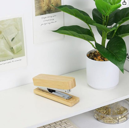 Wooden stapler on a desk with a plant and photos in the background