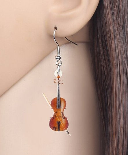 Violin-shaped earring on a person's ear with a plain background