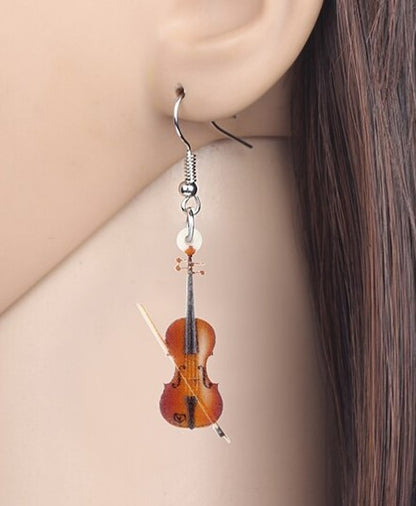 Violin-shaped earring on a person's ear with a plain background