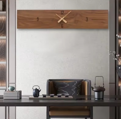 Wooden wall clock on a white wall above a wooden desk with decor items.