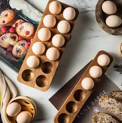 Wooden egg holder with eggs on a marble surface with pastries and bread.