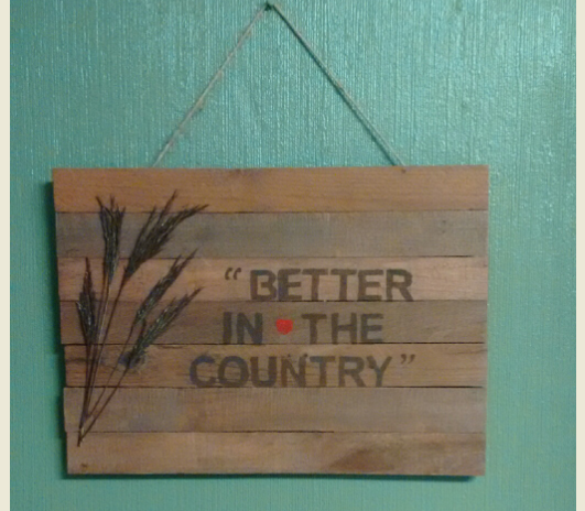 Pallet sign hanging on green wall