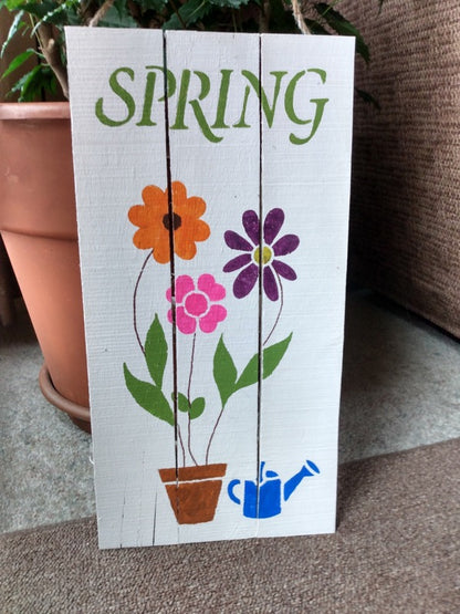 Spring-pallet sign on floor in front of pot
