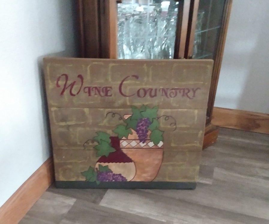 wine country wood sign staged in front of cabinet