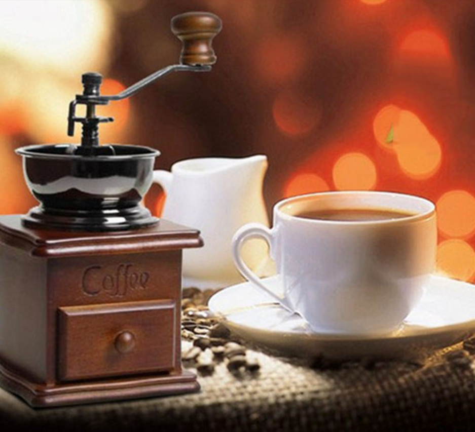 old fashioned coffee bean grinder next to coffee cup