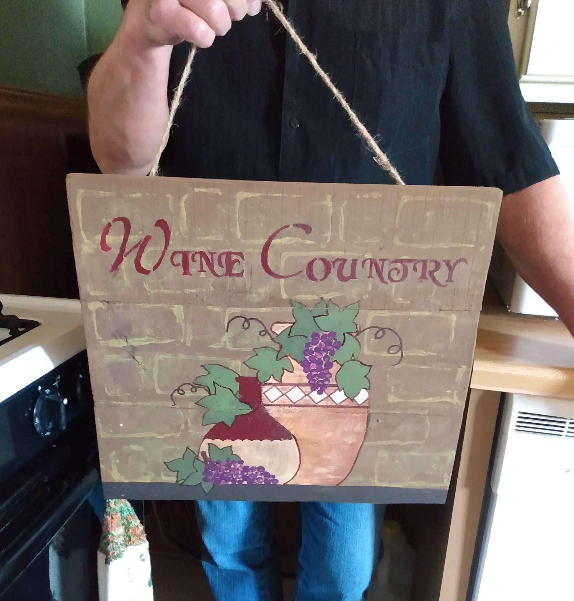 Larry holding wine country wood sign for sz dimension