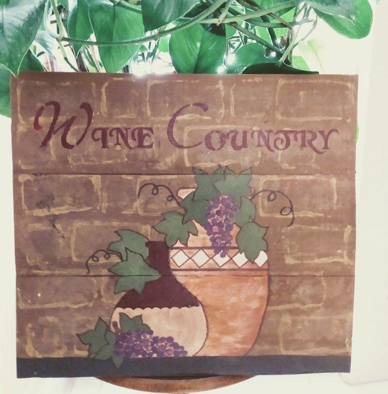 wine country wood sign cropped in front of plant